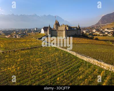 Blick aus der Vogelperspektive auf das mittelalterliche Schloss Aigle, umgeben von Weinbergen im Herbst, Kanton Waadt, Schweiz. Stockfoto
