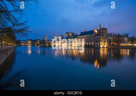 Blick auf den Binnenhof Komplex, der warm vor dem tiefblauen Dämmerhimmel leuchtet, reflektiert im ruhigen Wasser, Binnenhof, den Haag, Niederlande. Stockfoto