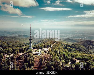 Blick aus der Vogelperspektive auf den Zagreb Fernsehturm, der hoch zwischen den üppigen grünen Hügeln und der fernen Skyline der Stadt steht, Zagreb, Kroatien. Stockfoto