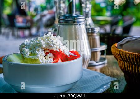 Eine Schüssel mit frischem Salat mit Tomaten und Hüttenkäse auf einem Holztisch. Stockfoto