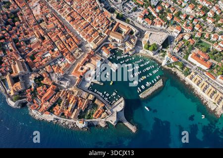 Aus der Vogelperspektive treffen die Terrakotta-Dächer auf die türkisfarbene Adria, die den alten Hafen von Dubrovnik, Kroatien, umgibt. Stockfoto