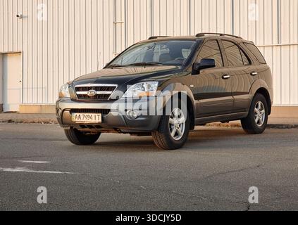 Der schwarze KIA Sorento parkte auf einer Straße. Dreiviertelansicht des dunklen SUV im Industrieviertel in Sonnenstrahlen. Stockfoto