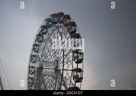 Nahaufnahme des mehrfarbigen Riesenrads während Dussehra Mela in Delhi, Indien. Unteransicht des Riesenradschwenkens. Riesenrad mit farbenfrohen Kabinen durin Stockfoto