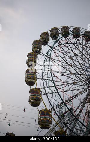 Nahaufnahme des mehrfarbigen Riesenrads während Dussehra Mela in Delhi, Indien. Unteransicht des Riesenradschwenkens. Riesenrad mit farbenfrohen Kabinen durin Stockfoto