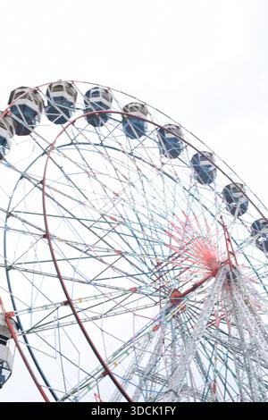 Nahaufnahme des mehrfarbigen Riesenrads während Dussehra Mela in Delhi, Indien. Unteransicht des Riesenradschwenkens. Riesenrad mit farbenfrohen Kabinen durin Stockfoto