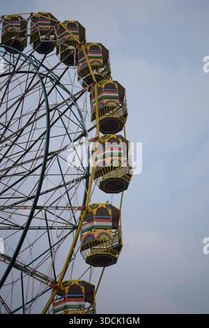 Nahaufnahme des mehrfarbigen Riesenrads während Dussehra Mela in Delhi, Indien. Unteransicht des Riesenradschwenkens. Riesenrad mit farbenfrohen Kabinen durin Stockfoto