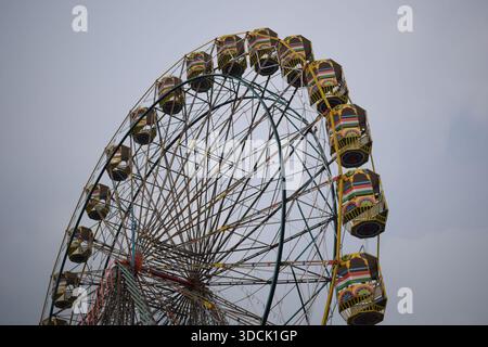 Nahaufnahme des mehrfarbigen Riesenrads während Dussehra Mela in Delhi, Indien. Unteransicht des Riesenradschwenkens. Riesenrad mit farbenfrohen Kabinen durin Stockfoto