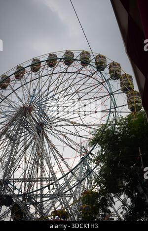 Nahaufnahme des mehrfarbigen Riesenrads während Dussehra Mela in Delhi, Indien. Unteransicht des Riesenradschwenkens. Riesenrad mit farbenfrohen Kabinen durin Stockfoto