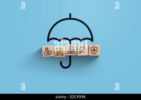 Versicherung, kreative Idee. Holzblöcke mit Ikonen der Familie, des Hauses, des Autos, der Kranken- und Geschäftsversicherung mit Regenschirm auf blauem Hintergrund, Ansicht von oben. Sa Stockfoto
