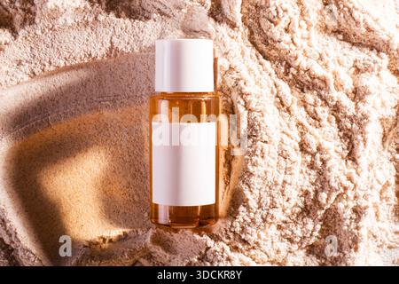Glaskosmetikglas spf 50 am Strand, beigefarbener Sandhintergrund. Konzept Beauty-Werbebroschüre, Mockup und Flat Lay Stockfoto