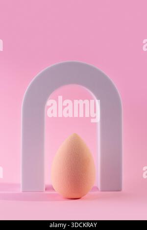 Pinkfarbener Schönheitsmixer isoliert auf rosafarbenem Hintergrund mit Bogen. Pinkfarbener Mischschwamm für Make-up. Minimales Denken. Minimal Stockfoto