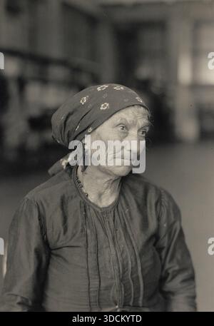Italienisch auf Ellis Island - Portrait of an enlderly Lady 1920 - dieses Foto zeigt einen italienischen Immigranten auf Ellis Island, dem wichtigsten Einreiseort für Millionen von europäischen Einwanderern in die Vereinigten Staaten im späten 19. Und frühen 20. Jahrhundert. Das Bild aus dem Jahr 1920 spiegelt die unterschiedlichen Altersstufen der Zuwanderer wider, einschließlich älterer Erwachsener, die sich mit der Familie wieder vereinen oder neue Möglichkeiten finden möchten. Ellis Island war nicht nur ein Verarbeitungszentrum, sondern auch ein Symbol der Hoffnung und des Übergangs und markierte den Beginn eines neuen Lebens in Amerika inmitten der Herausforderungen der Einwanderung, Anpassung und Gemeinschaft b Stockfoto