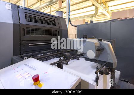 Der Papierladebereich einer großen Offsetdruckmaschine mit einem hohen Stapel weißer Blätter, die produktionsbereit sind. Stockfoto