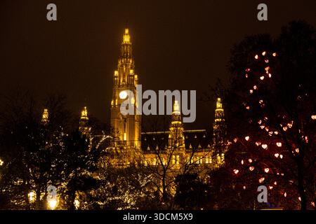 Beleuchteter gotischer Rathausturm in Wien bei Nacht mit festlichen Lichtern während der Weihnachtszeit. Stockfoto
