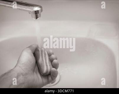 Der Mann wäscht Hand unter fließendem Wasser aus dem Wasserhahn im Waschbecken Stockfoto