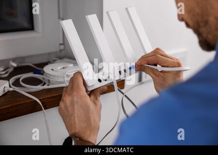 Drahtloses Internet. Servicetechniker, der das netzwerkkabel mit dem WLAN-Router zu Hause verbindet Stockfoto