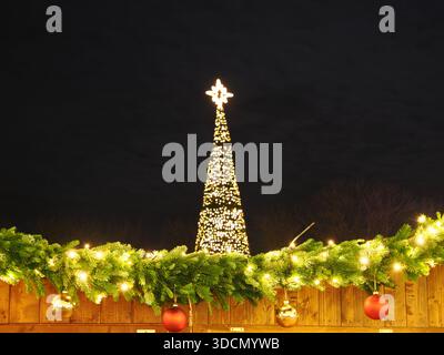 Beleuchteter Weihnachtsbaum bei Nacht mit festlicher Girlande, Ornamenten und Weihnachtsbeleuchtung Stockfoto