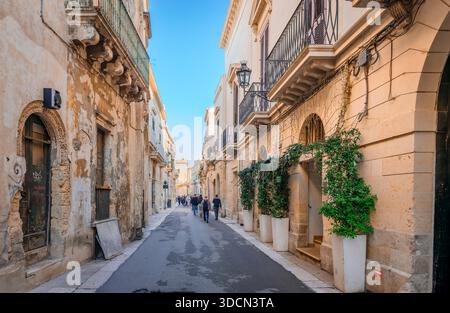 Die Menschen laufen auf der Via Principi Di Savoia, einer schmalen Straße im Zentrum des historischen Zentrums von Lecce in Italien, mit alten und mittelalterlichen Gebäuden. Stockfoto