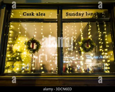 London, England – traditionelles Pub-Fenster mit Weihnachtsmärchen und Kränzen, festliche Gastfreundschaft-Dekoration Stockfoto