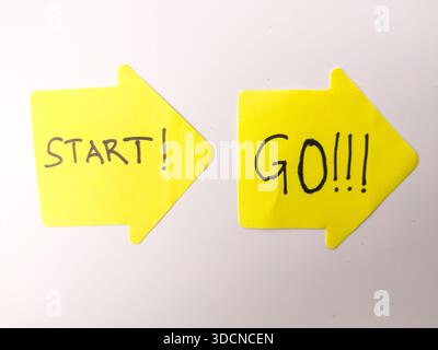 Zwei gelbe, pfeilförmige Haftnotizen mit motivierenden Botschaften, die zum Handeln und zum Fortschritt ermutigen. Stockfoto