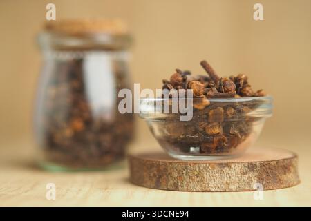 Nelken in Glasschale mit Glas auf Holzoberfläche Stockfoto