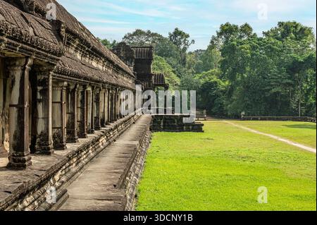 Asiatisches Reisethema mit Seitenwinkel der historischen Kolonnadenstruktur mit sich wiederholenden Säulen und verwitterten Wänden im tropischen Park im Sommer Stockfoto