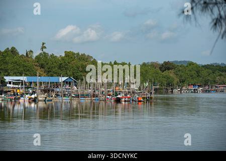 Balok, Malaysia - 18. Oktober 2025 - Foto von traditionellen Fischerbooten, die entlang eines tropischen Ufers angedockt sind und sich unter einer blauen Ske auf dem Wasser spiegeln Stockfoto