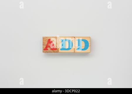 Bemalte Buchstabenwürfel, die so angeordnet sind, dass die Abkürzung HINZUGEFÜGT WIRD Stockfoto