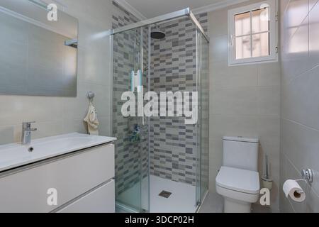 Sauberes, modernes Badezimmer mit Glasdusche, Kosmetiktoilette und gefliesten Wänden Stockfoto
