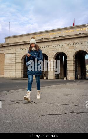 Junge kaukasische Frau, die im Winter durch das äußere Schlosstor Wien geht Stockfoto