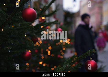 Lebhafte weihnachtsszene mit roten Kugeln und goldenem Bokeh, festlicher Atmosphäre und verschwommenen Passanten in gemütlicher Winterkleidung, Festlichkeit und Zauber Stockfoto