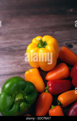 Farbenfrohe Anordnung von Paprika auf Holztisch mit gelben, grünen, roten und orangen Paprika in natürlichem Licht, die lebendige Töne A hervorheben Stockfoto