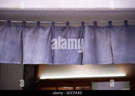 Der Vorhang-ähnliche Stoff, der vor traditionellen japanischen Restaurants und Geschäften hängt, dient nicht nur als Schild, sondern hat eine größere Bedeutung, Stockfoto