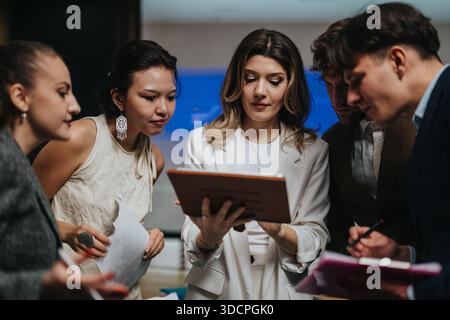 Geschäftskollegen treffen sich um ein Tablet, um gemeinsam Ideen zu diskutieren und Projekte zu planen Stockfoto