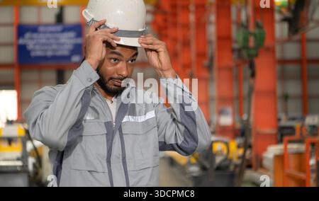 Industriearbeiter, der in einem großen Metallrohr in einer Fabrik einen Schutzhelm trägt || Modell veröffentlicht Stockfoto