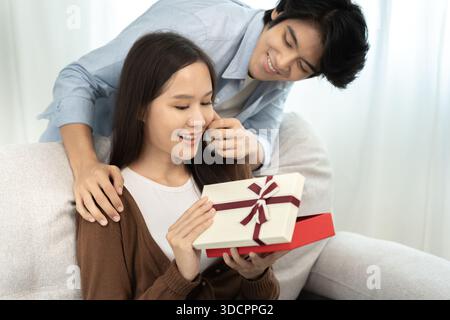 Paare Familie Lächeln und glückliches offenes Geschenk, Überraschung, Kuscheln, warme Umarmungen, junge Liebe, verheiratetes Paar, warme Familie. Ehemann und Frau sind verliebt, so lustig in mir Stockfoto
