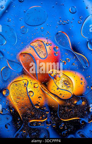 Blaue Flüssigkeit mit mehrschichtigen Ölblasen und warmen Reflexen, abstrakter Vorratshintergrund. Stockfoto