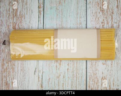 Verpacktes Spaghettibündel, das auf einer dickflüssigen Holzoberfläche platziert wird, zeigt die Form der Nudeln, das klare Produktlayout und die Klarheit der Zutaten für kulinarische Themen, b Stockfoto