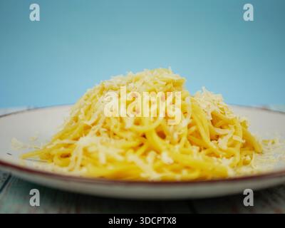 Spaghetti-Teller mit geriebenem Parmesankäse auf blauem und weißem Hintergrund, vertikales italienisches Pasta-Bild für Restaurantplakate, Menüs und geselliges Med Stockfoto