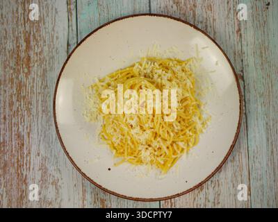 Blick von oben auf die weiße Platte mit gekochten Spaghetti und geriebenem Parmesankäse auf rustikaler Holzoberfläche, klassische italienische Pasta für Hausmannskost oder r Stockfoto