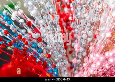 Glänzende Perlengirlanden in lebhaften Weihnachtsfarben vor weichem Hintergrund. Die glänzenden Perlen erinnern an ein festliches Weihnachtsambiente. Verschiedene Glitzstränge Stockfoto