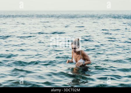 Frau Ozeanwasser, junge Frau, die während der Sommerferien aus erfrischendem Meerwasser auftaucht, mit Kopierraum. Stockfoto