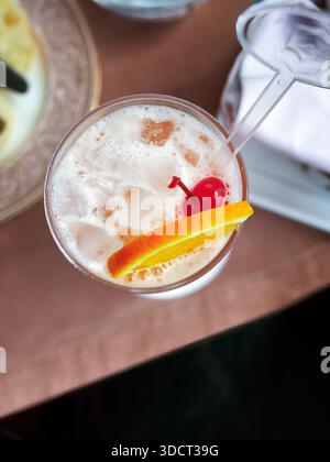 Ein lebendiger, erfrischender Punsch aus roten Früchten oder Cocktail, serviert in einem hohen Glas. Ähnelt einem Mai Tai, Tequila Sunrise oder Erdbeermocktail, gefüllt mit Crys Stockfoto