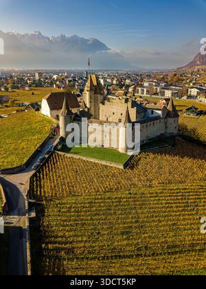 Blick aus der Vogelperspektive auf das Schloss Aigle, umgeben von Weinbergen im Herbst, Kanton Waadt, Schweiz. Stockfoto