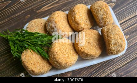 Frisch gefrorene panierte Fischkuchen. Runde, halbfertige Produkte, fertig zum Kochen. Fisch Und Meeresfrüchte. Stockfoto