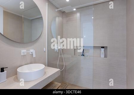 Stilvolles, neutrales Bad mit eleganten Armaturen, geräumiger Glasdusche und klarem, modernem Design Stockfoto