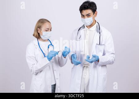 Zwei Ärzte in Masken sprechen und halten ein digitales Tablet Stockfoto