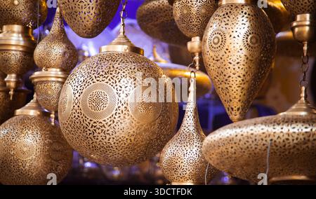 Marokkanische Messinglampen mit feinen Gravuren hängen in einem traditionellen Fès-Geschäft und zeigen komplizierte Muster unter warmer Beleuchtung. Stockfoto