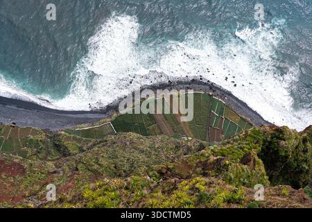 Blick von oben auf Küste und Vegetation, aus der Vogelperspektive auf grüne Hänge, die auf turbulentes Meereswasser treffen, Aufnahmen von Drohnen mit rauen en en Stockfoto