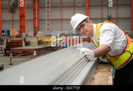 Industriearbeiter, der in einem großen Metallrohr in einer Fabrik einen Schutzhelm trägt || Modell veröffentlicht Stockfoto